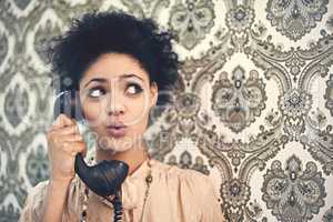 Oh, really. Studio shot of a young woman in a vintage outfit talking on an old-fashioned telephone.