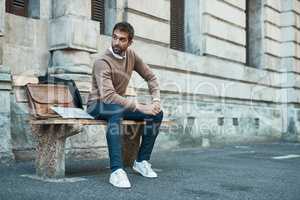 The town is his office. Full length shot of a handsome businessman sitting on a bench in town.