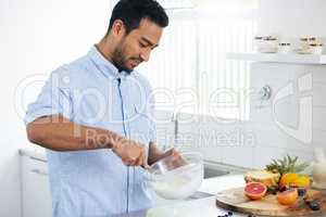 Im whipping up something delicious and nutritional. Shot of a man making himself a smoothie at home.