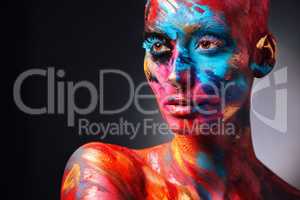 Wear your colours boldly. Shot of an attractive young woman posing alone in the studio with paint on her face and body.
