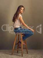 Be a perfectly put together mess if you want to. Studio shot of a beautiful young woman sitting on a stool against a plain background.