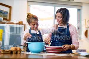 And now to sprinkle in the magic ingredient. Shot of a mother and her little daughter baking together at home.