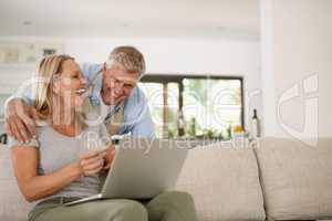 Laughter is our secret to a everlasting love. Shot of a mature couple laughing at something they saw on the laptop.