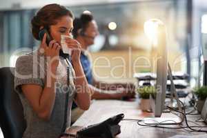 Dont delay going to the doctor when youre ill. Shot of a young businesswoman blowing her nose while talking on a phone in an office.