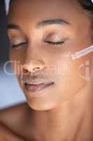 At ease in her skincare regime. Closeup shot of an attractive young woman using a dropper to apply serum to her face.