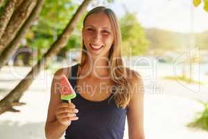 Its my favourite summer snack. Portrait of an attractive young woman enjoying a popsicle on the beach.