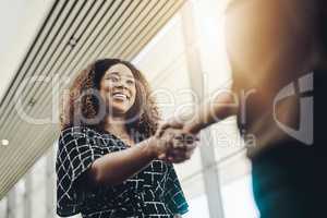 Welcome to the company. Low angle shot of an attractive young businesswoman shaking hands with an associate in a modern workplace.