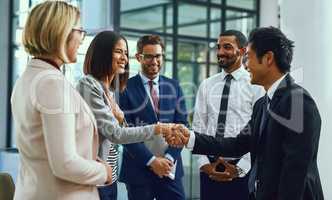 Its an honour to be working alongside the best. Shot of businesspeople shaking hands in an office.
