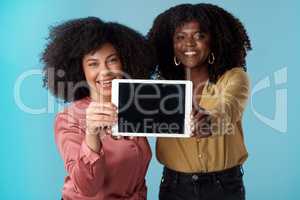Fire up the wifi, youre going to want to download this. Studio shot of two young women holding a digital tablet with a blank screen against a blue background.