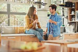 Catching up in the kitchen. Shot of an affectionate young couple conversing in their kitchen.