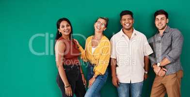 Optimism is a strategy for making a better future. Portrait of a group of young designers standing together against a green background.