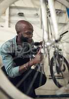 Making this bike feel brand new. Shot of a handsome young man crouching alone in his shop and repairing a bicycle wheel.