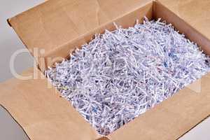 Shredded paper is great for packing. Studio shot of shredded paper in a cardboard box against a grey background.