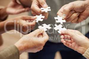 Problem solving as a team for optimum efficiency. Closeup shot of a group of unrecognisable people joining puzzle pieces together.