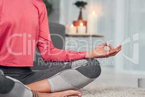 Balancing my chakras. Cropped shot of an unrecognizable woman sitting cross legged and meditating in her living room while at home.