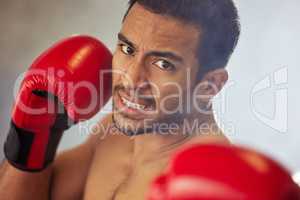 Striking swiftly. Cropped portrait of a handsome young male boxer striking towards the camera during a fight in the ring.