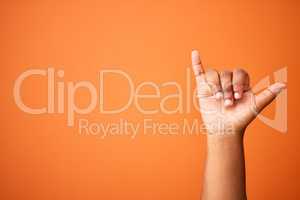 Lifes great. Shot of an unrecognizable person showing a shaka sign against an orange background.