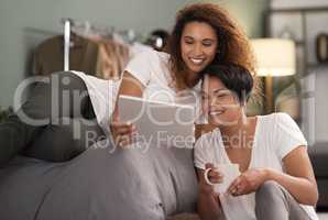 Ill keep choosing you. Shot of a young lesbian couple using a tablet while relaxing in their bedroom.