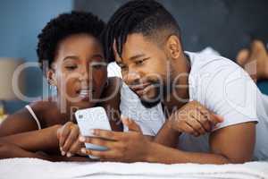 The moment we met, we made a lifelong connection. Shot of a young couple using a smartphone in bed at home.