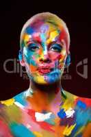 Adding colour makes all the difference. Studio shot of a young woman posing with multi-coloured paint on her face.