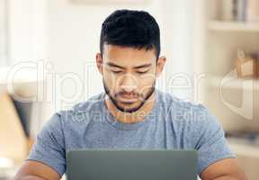 Networking online. Shot of a young businessman using a laptop in an office at work.