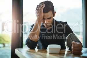 His blood pressure is pushing up. Shot of a young businessman checking his blood pressure in an office.