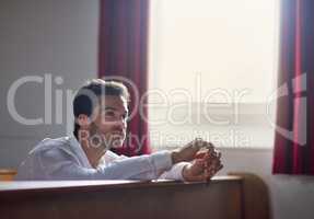 Faith is the light you feel during dark times. Shot of a thoughtful young man sitting in a church.