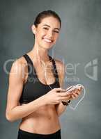 Gotta sort my playlist first. Studio portrait of a sporty young woman listening to music against a grey background.