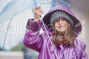 The cold never bothered me anyway. Portrait of a little girl standing under an umbrella outside.