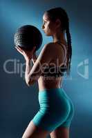 Why be moody when you can work your booty. Studio shot of a sporty young woman holding an exercise ball against a blue background.