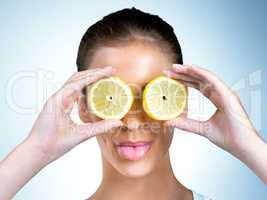 When life gives you lemons, pucker up. Shot of a health-conscious young woman posing with lemons over her eyes in studio.