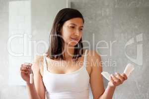 What should I use today. Shot of a young woman holding a tampon and sanitary towels at home.