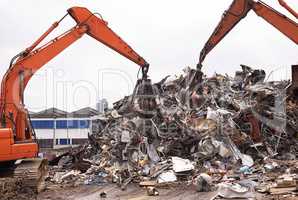Industrial re-purposing. Cropped shot of two excavators sorting through a pile of scrap metal.