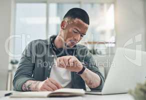 Dont let the fear of losing stop you. Shot of a young business man checking his watch in a modern office.