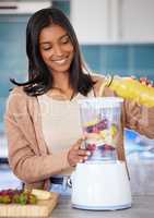 Whipping up a delicious drink in just a few minutes. Shot of a young woman preparing a healthy smoothie at home.