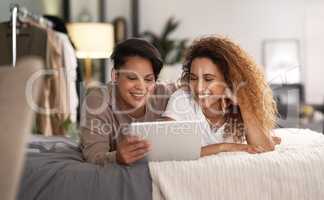 Do not disturb our quality time. Shot of a young lesbian couple using a tablet while relaxing in their bedroom.