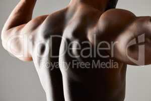 Stop wishing. Start doing. Studio shot of a unrecognizable male flexing his back muscles against a grey background.