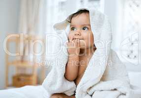 I taste so fresh. Shot of an adorable baby covered in a towel after bath time.