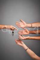 Who wants to drive. Studio shot of unidentifiable hands reaching for a set of keys against a gray background.