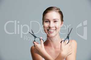 Short hair isnt just for the guys. Studio portrait of an attractive young woman holding scissors against a gray background.