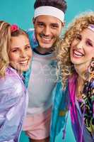 Ready for some 80s fun. Shot of three young people posing together in 80s clothing against a blue background.