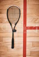 As durable as any squash player deserves. Shot of a squash racquet on the floor of a squash court.