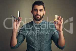 Beard under construction. Studio shot of a handsome young man holding a straight razor and a shaving brush in his hands.