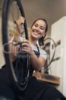 Theres nothing a brand new tyre cant fix. Shot of an attractive young woman standing alone in her shop and repairing a bicycle wheel.