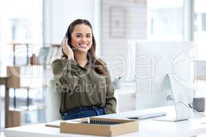 Super helpful from the first hello. Portrait of a young businesswoman using a headset and computer in a modern office.
