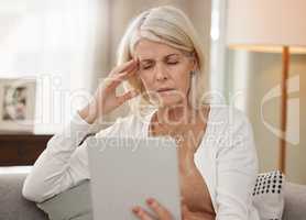 Dear Internet, what do I do about this headache. Shot of a mature woman using a digital tablet and feeling unwell at home.