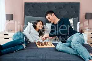 First rule of surviving lockdown Have fun. Shot of a young couple playing a game of chess at home.