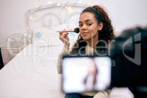 Ill show you how to achieve a flawless look. Shot of a young woman doing her makeup while recording a video for her blog.