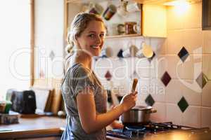 My cooking is quite tasty, if I say so myself. Portrait of an attractive young woman cooking at home.
