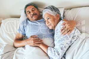 In love since the day we met. Shot of a relaxed mature couple lying in bed together at home in during the morning hours.